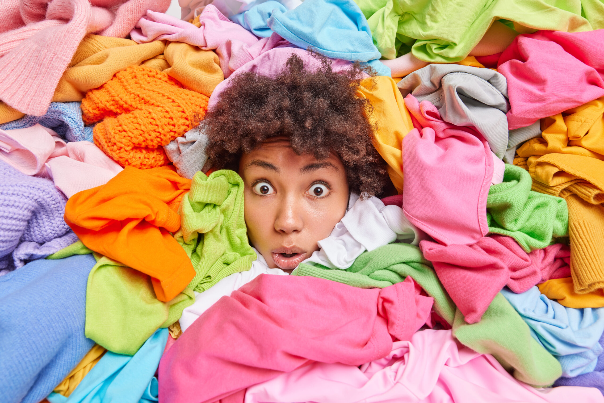 Overwhelmed Afro American Woman Gives Advice Recycle Your Old Clothes Sticks Out Head Through Multicolored Clothing Surrouunded By Unwearable Items Collected Donation Textile Recycling Scaled